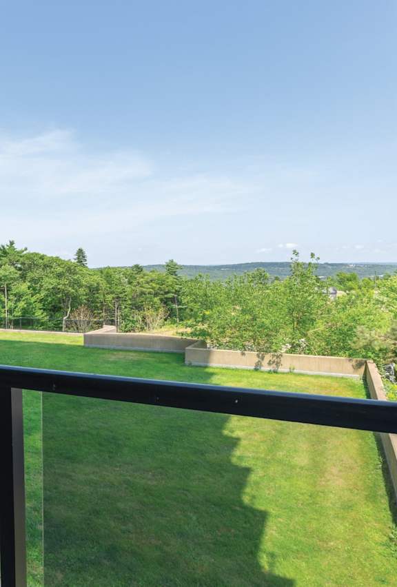 A balcony overlooks a green lawn and trees.