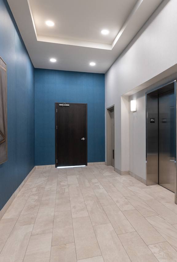 A hallway with a blue wall and a large painting on the left side.