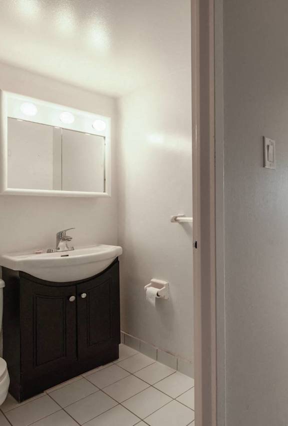 A bathroom with a sink, toilet, and mirror.