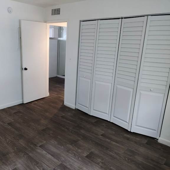 A room with a white door and a white wardrobe with a mirror.