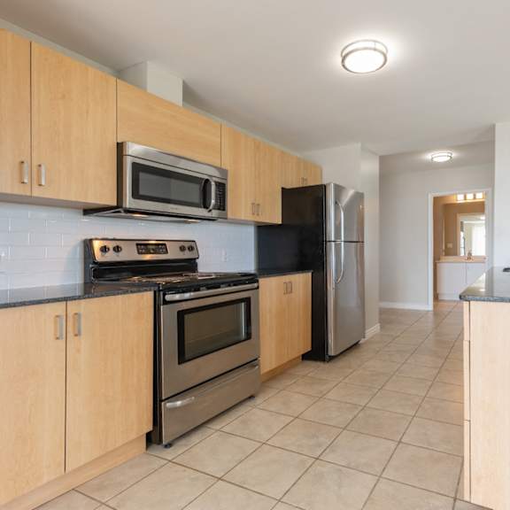 A kitchen with wooden cabinets and a stainless steel refrigerator.