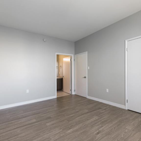 A room with a white door and a brown floor.