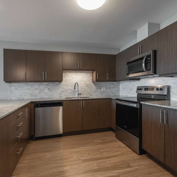 A kitchen with wooden cabinets and a marble countertop.
