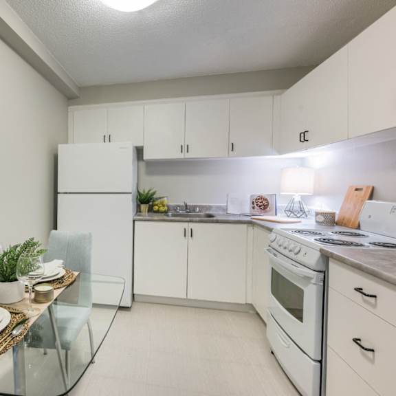 A modern kitchen with a glass table and white cabinets.