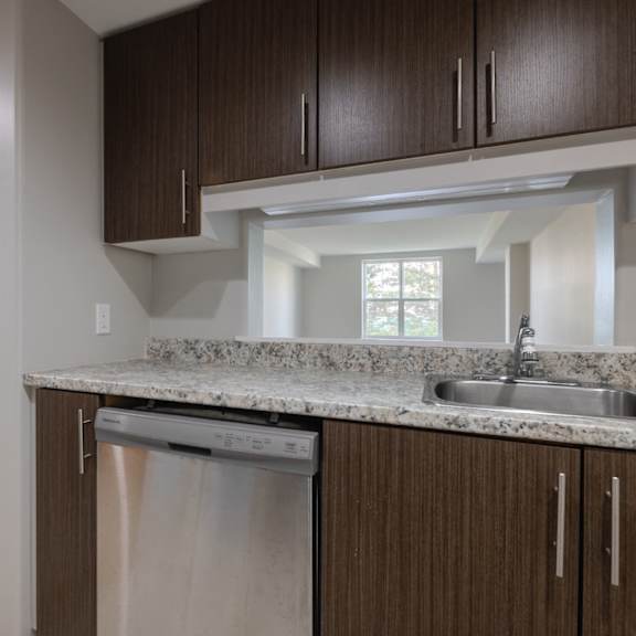 A kitchen with brown cabinets and a stainless steel dishwasher.