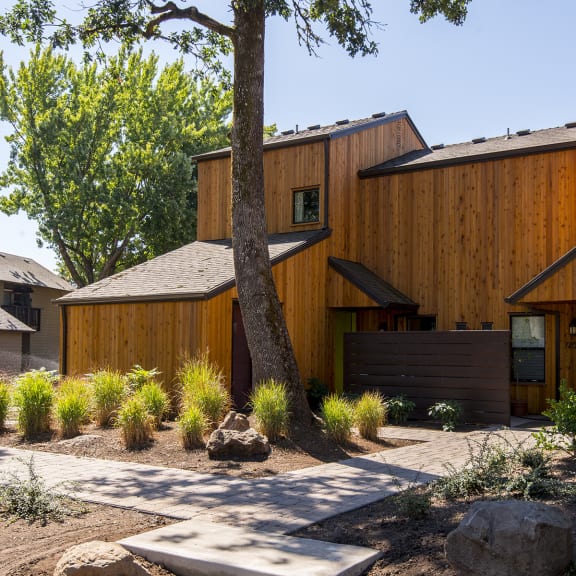 a wooden house with a walkway and a tree