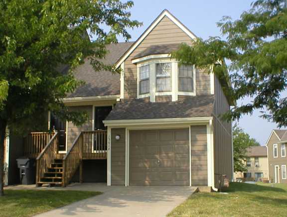 Yeakel Townhome featuring a house with a brown garage door and a matching brown roof.
