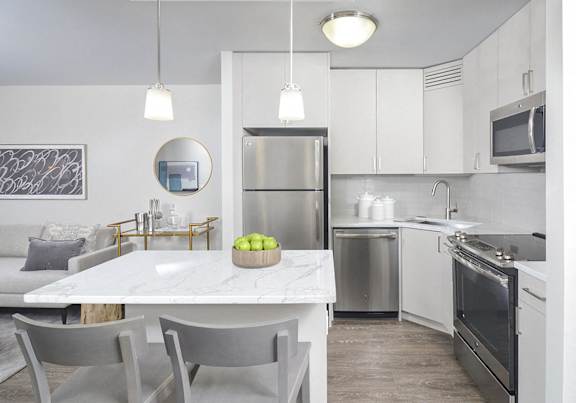 A modern kitchen with a marble table and stainless steel appliances.
