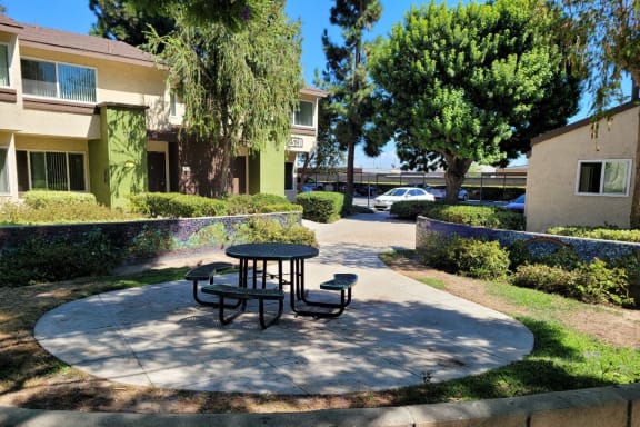 a patio with a table and benches in front of a building