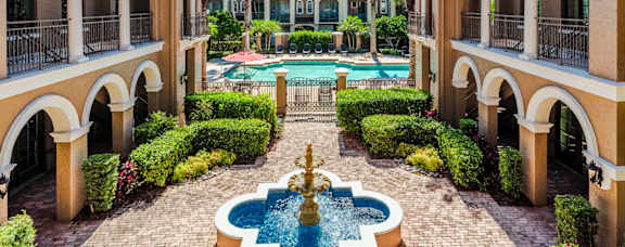 Tranquil courtyard fountain framed by palm trees and Mediterranean-style architecture.
