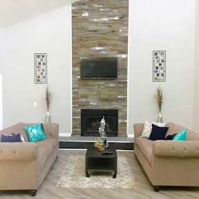A living room with a stone fireplace and two couches.