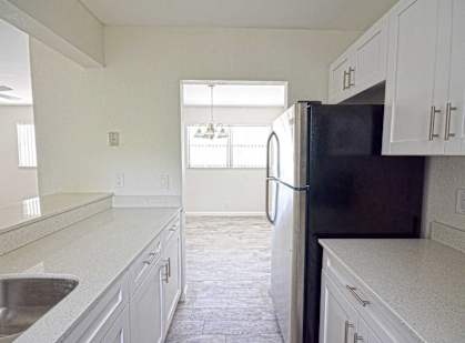 an empty kitchen with white cabinets and a black refrigerator