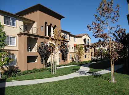 Apartment complex with a green lawn and trees.