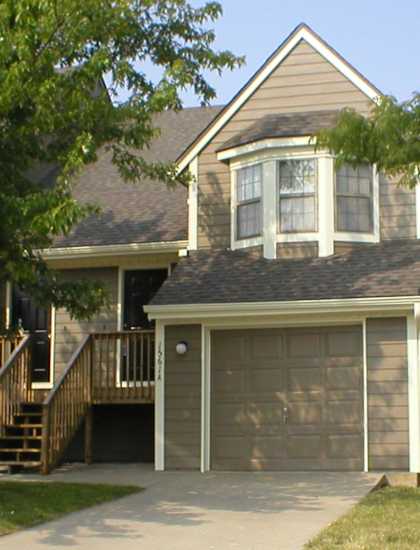 Yeakel Townhome featuring a house with a brown garage door and a matching brown roof.