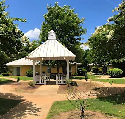 A gazebo is surrounded by trees and bushes.