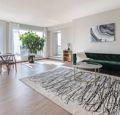 a living room with a green couch and a table and a large window