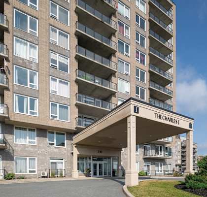 The entrance to The Charles apartment building with a blue sky in the background.