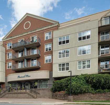 A large apartment building with a brown brick facade and a sign that says "Pinnacle Place.".