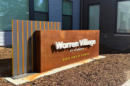 A sign that says Warren Village at Alameda with a brown background.