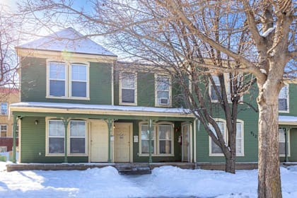 A green house with a tree in front of it. at Meeker Commons Apartments , Greeley