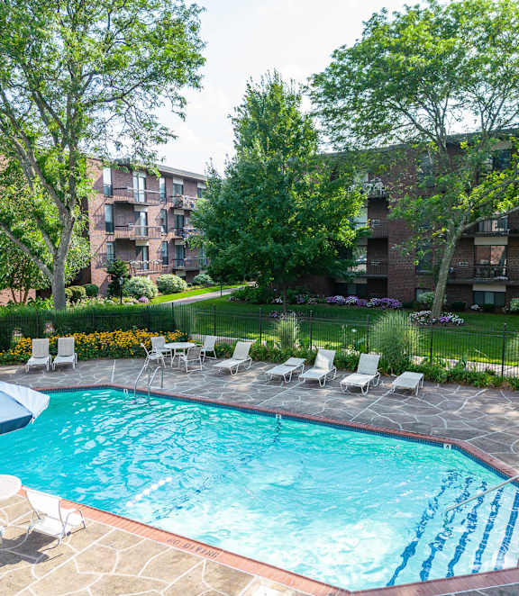 A swimming pool surrounded by sun loungers in a residential area.