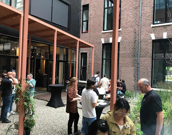 A group of people are gathered outside a building with a brick facade.