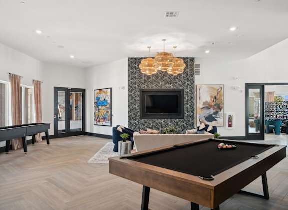 A pool table is in the middle of a room with a fireplace and a chandelier.