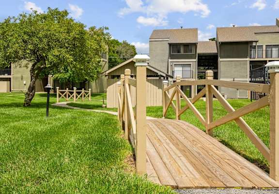 a wooden bridge leading to an apartment complex