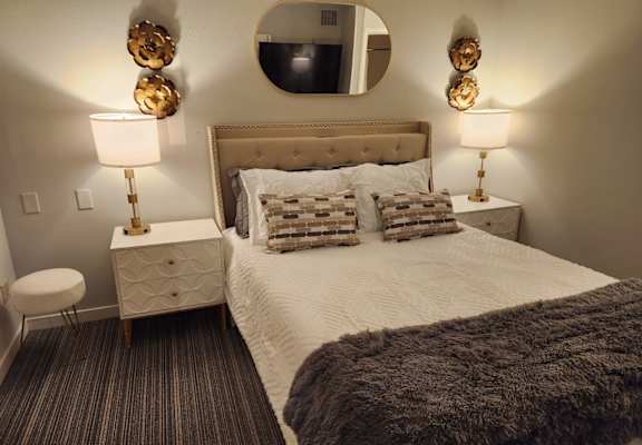 a bedroom with a bed and lamps and a mirror