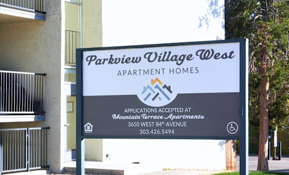 A sign for Parkview Village West Apartment Homes is displayed in front of a building.