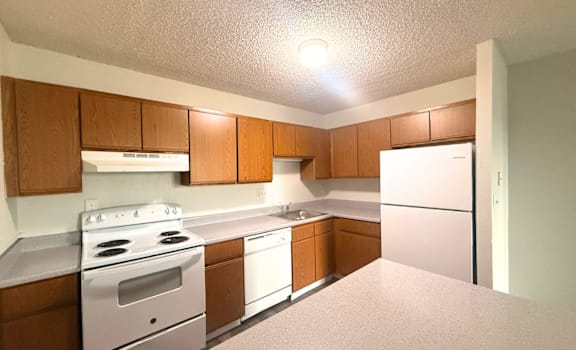 A kitchen with white appliances and wooden cabinets.