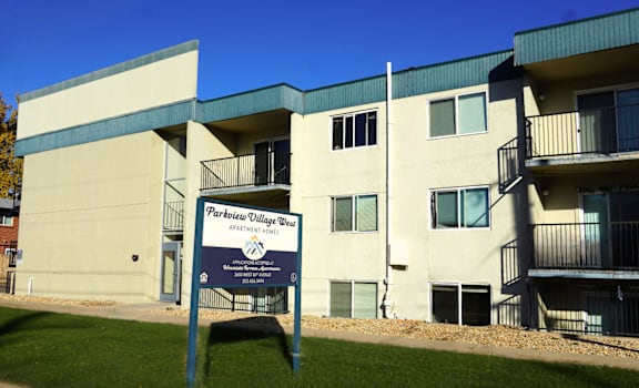 A sign in front of a building that says Parkview Village Apartments.