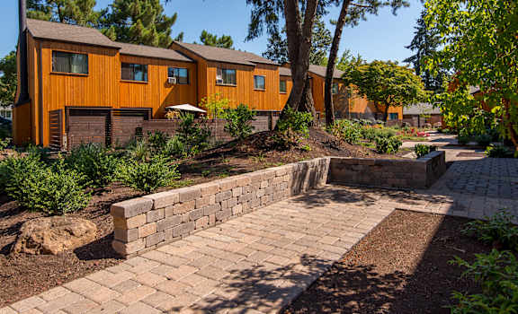 a brick walkway leading up to a house with trees and a courtyard