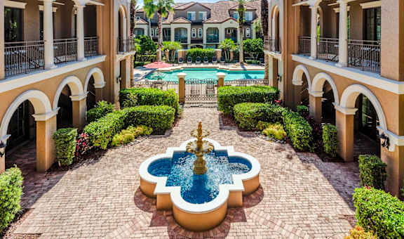 Tranquil courtyard fountain framed by palm trees and Mediterranean-style architecture.