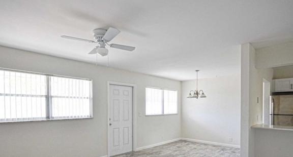 an empty living room with a ceiling fan and a window