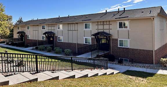 An apartment building with a yard surrounded by a black wrought iron fence in the Cambridge Apartments complex.