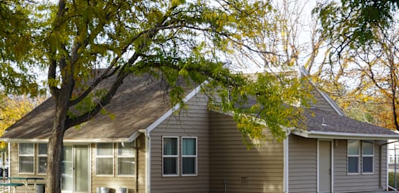 A house with a tree in front of it. at Grand Manor Apartments , Grand Junction