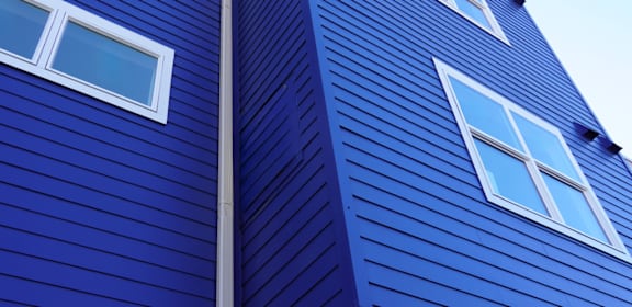 A blue wooden building with white windows.