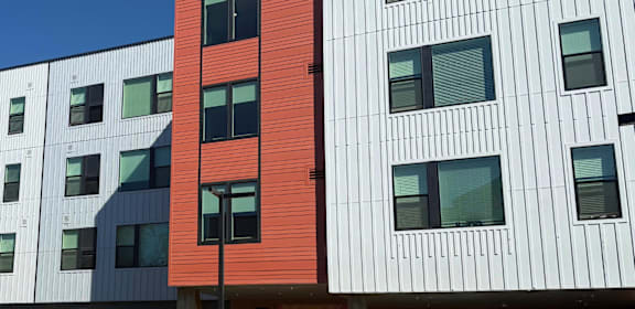 A red building stands out next to white buildings with black windows.