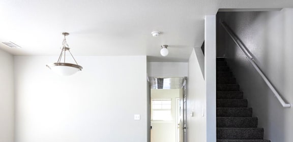 A room with a staircase and a light hanging from the ceiling. at Meeker Commons Apartments , Greeley