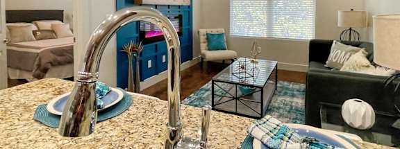 Kitchen Sink and Living Room with Blue Accents in One-Bedroom Apartment