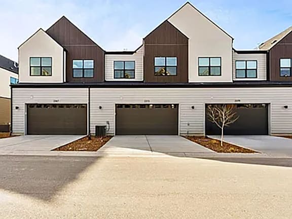 A modern house with a large front yard and two garages.