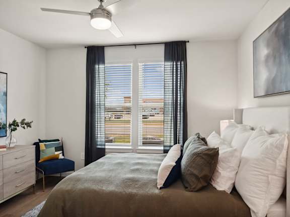 A bedroom with a large bed and a view of the city through the window.