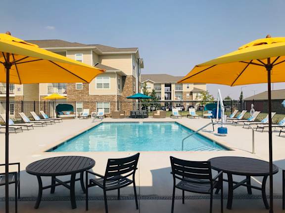 A pool area with chairs and umbrellas in front of apartment buildings at Salish Flats APARTMENTS, Airway Heights, Washington, 99001
