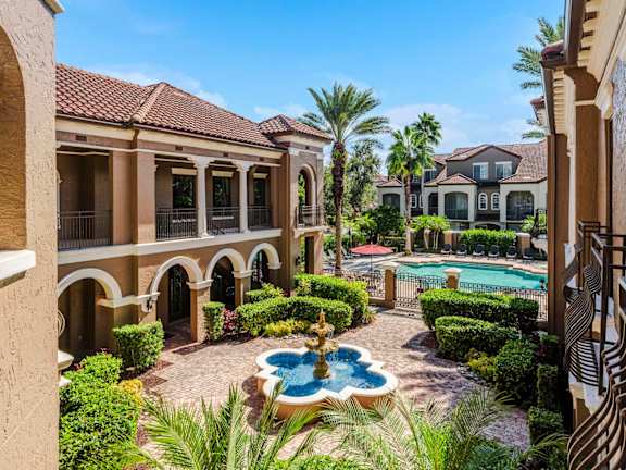 Courtyard fountain leading to the resort-style pool and palm-lined architecture.