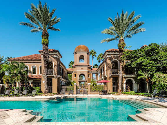 Grand pool courtyard framed by Mediterranean buildings and a central tower
