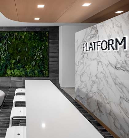 a wall of plants and a white table with white chairs in front of it