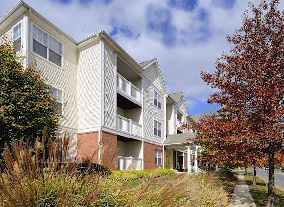A building with a balcony and a tree with red leaves.