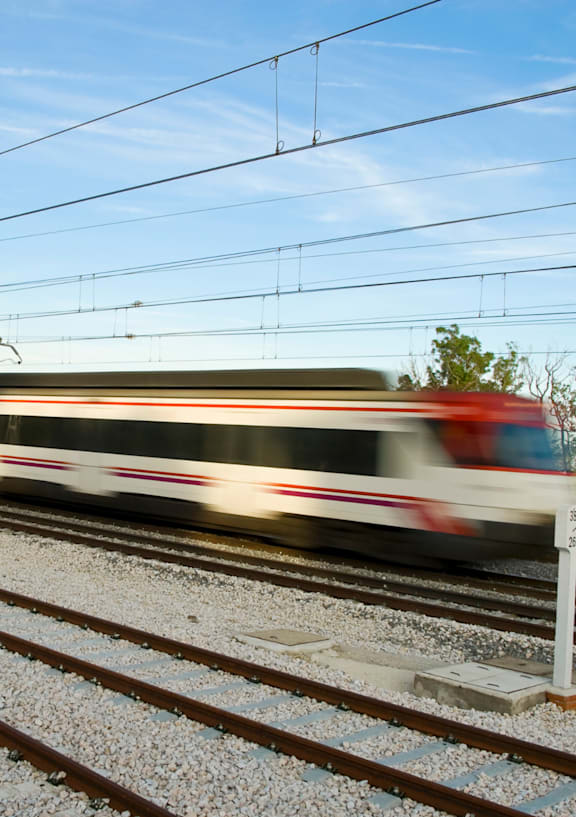 A train is speeding along the tracks on a sunny day.