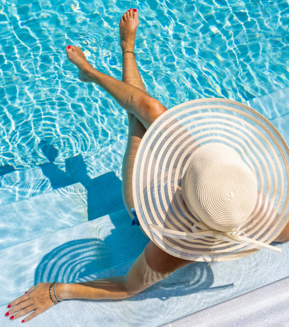 a woman in a floppy hat sitting on the side of a pool at Hamilton at Eagleview, Exton